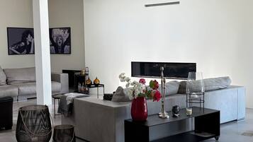 A modern living room with a grey sofa, a coffee table, and a red vase with flowers.