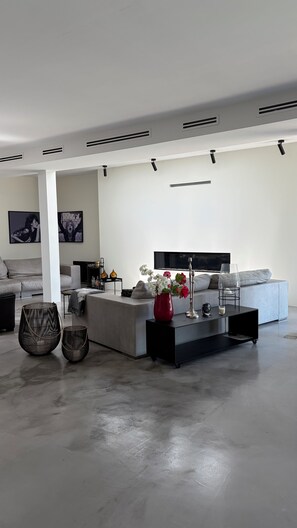 A modern living room with a grey sofa, a coffee table, and a red vase with flowers.