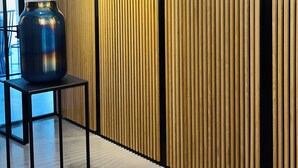 A modern interior with a wooden panel wall, a black metal table with a vase, and a polished floor.