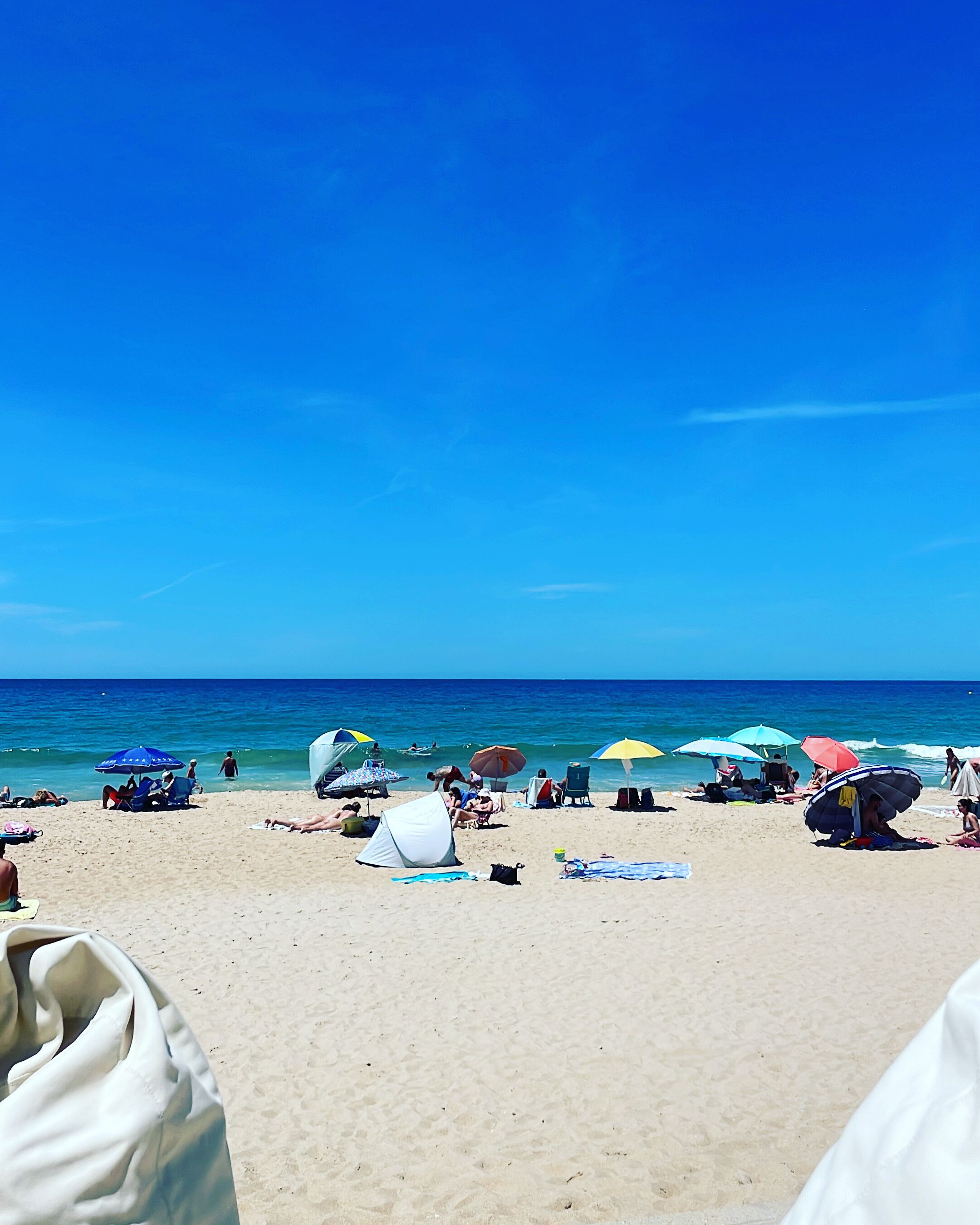 A beach with tents and umbrellas, sandy beach, and the ocean.
