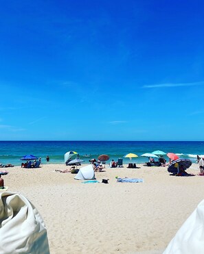 A beach with tents and umbrellas, sandy beach, and the ocean.
