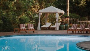 Un área de piscina con sillones de descanso y una toldo.