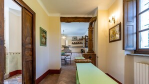 A hallway with a wooden door, a green bench, and a kitchen area in the background. - Villa Harmonia - Luxury Rooms - Salvia Suite - AC - By Guestaly (Dormelletto)