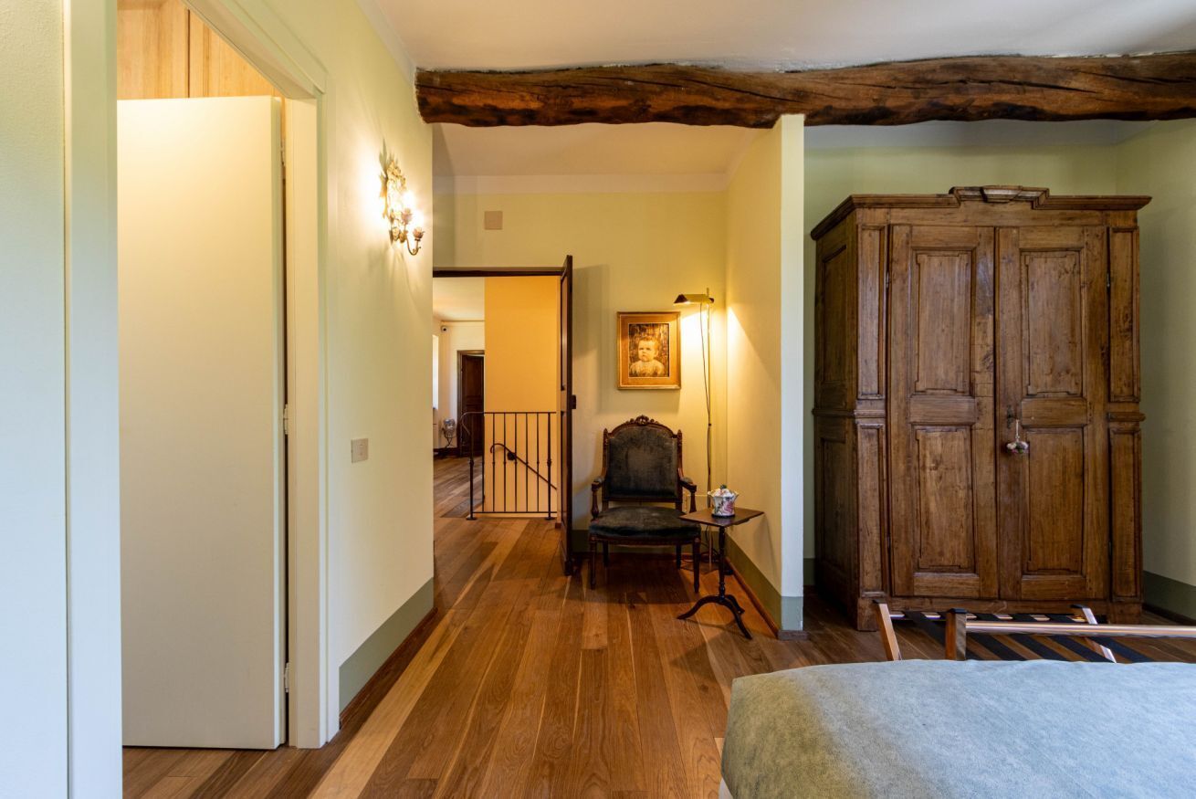 Un couloir avec un plancher en bois, une chaise, une table et une armoire.
