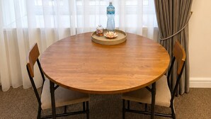 A round wooden table with a water bottle and a small container, surrounded by four chairs. - Sunlay City (Rīga)