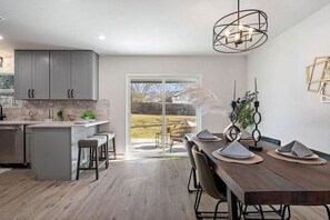 Een moderne keuken met grijze kastjes, een centraal eiland en een eethoek met een houten tafel en stoelen.