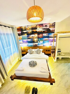 Ein Hotelzimmer mit einem Bett, einer Fotowand, einer Pendelleuchte und einem hölzernen Kopfteil.