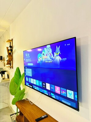 Ein Flachbildfernseher an der Wand, der einen Kindersender mit Zeichentrickfiguren zeigt.