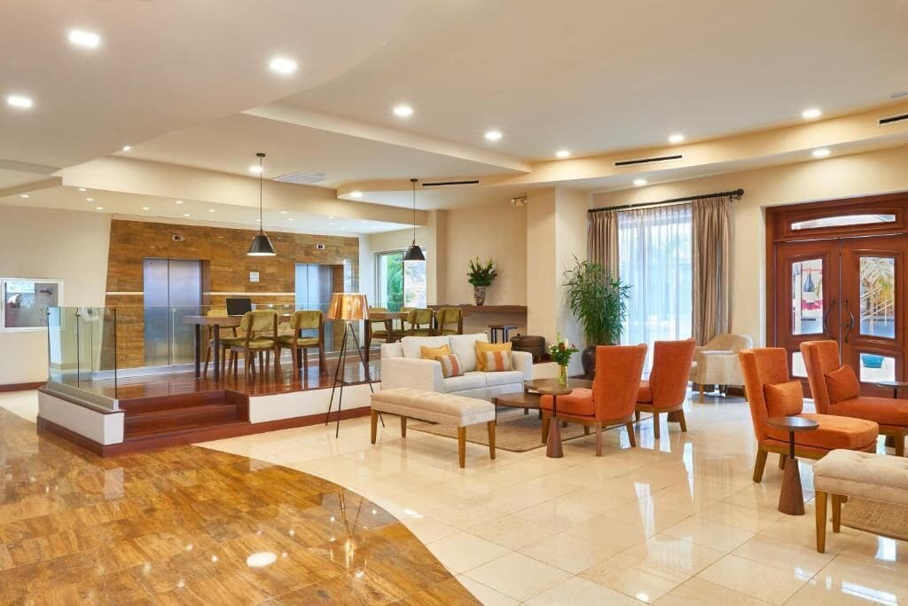 A spacious lobby with a reception desk, seating area, and a staircase leading to an upper floor.