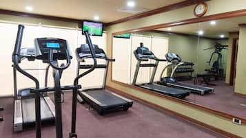 A gym with treadmills, a television, and exercise equipment.
