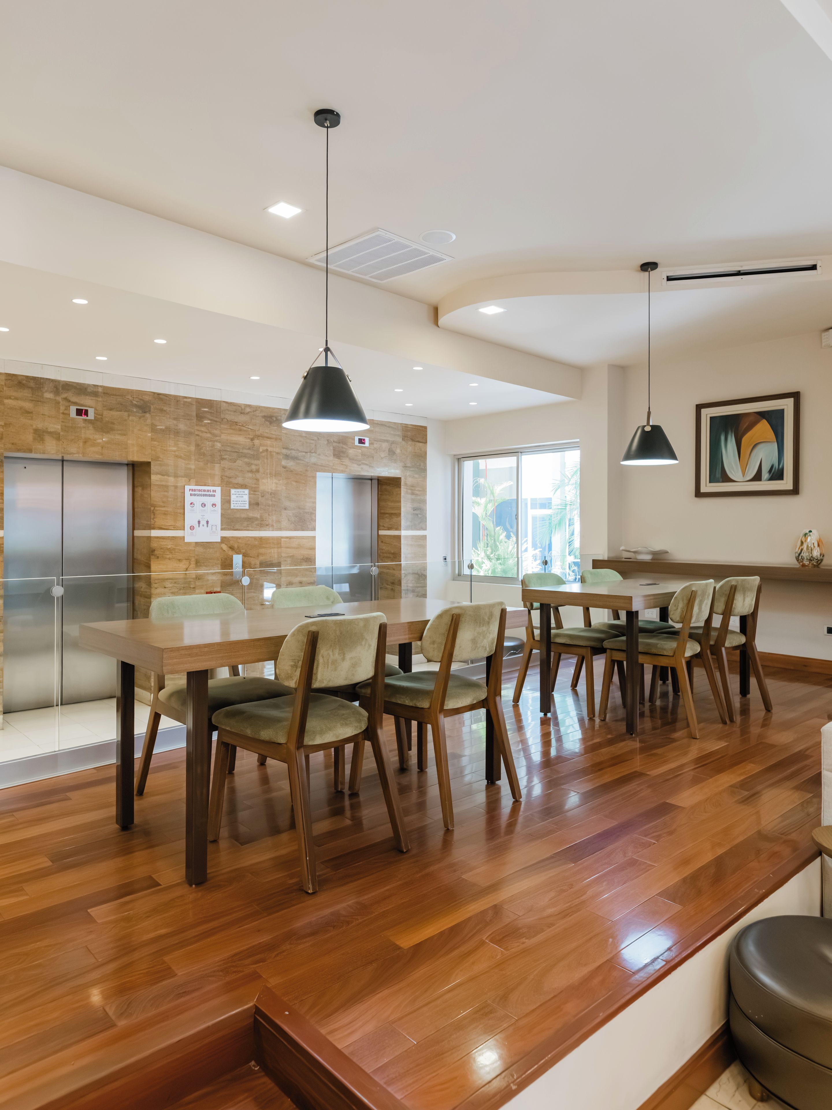 A modern kitchen with wooden flooring, a dining area with chairs, and a large window.
