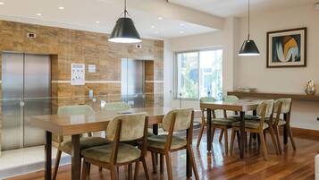 A modern kitchen with wooden flooring, a dining area with chairs, and a large window.