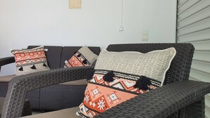 Ein Korbssessel mit vielen Kissen, einem Wanddimmer und einer Steckdose.