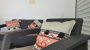 A wicker sofa with multiple cushions, a wall-mounted light switch, and a power outlet. - Villa Amoreira: The Perfect Retreat (Óbidos)