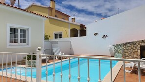 Ein Swimmingpool mit weißem Zaun, einem weißen Stuhl und einer Steinmauer.