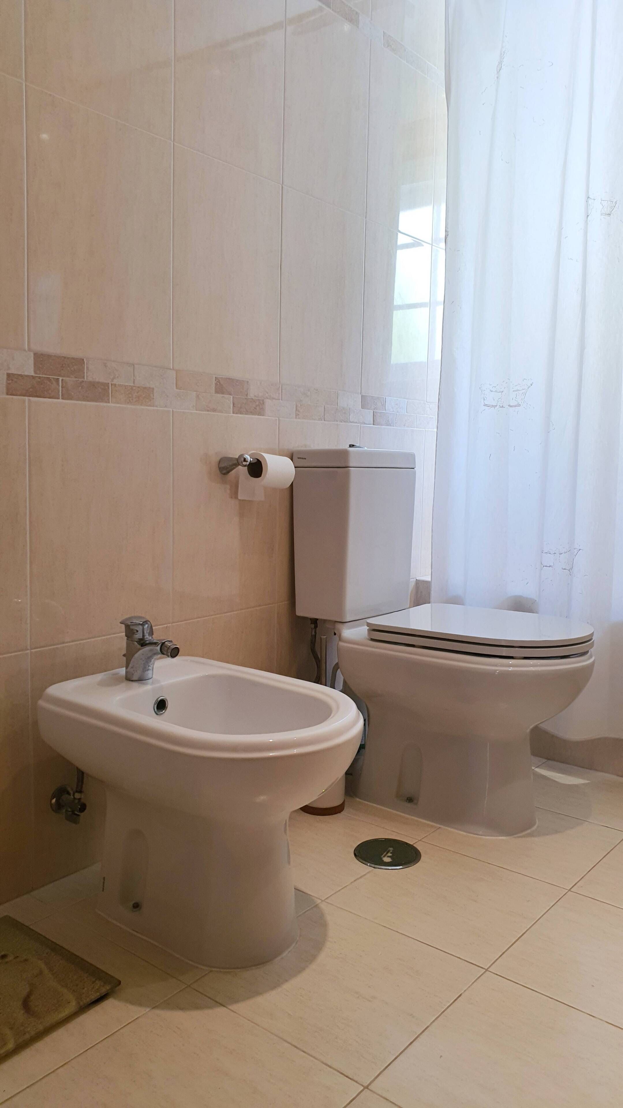 A bathroom with a bidet, toilet, and a sink.
