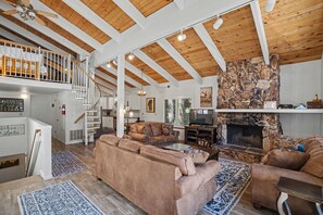 A spacious living area with a high ceiling, wooden beams, a fireplace, and a cozy seating arrangement. - Steps to Heavenly | Mountain Chalet w/ Hot Tub (South Lake Tahoe)