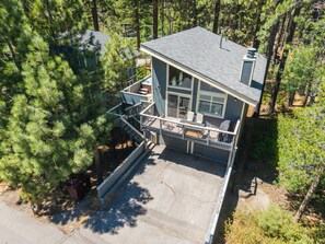 A two-story house with a balcony, surrounded by dense pine trees. - Steps to Heavenly | Mountain Chalet w/ Hot Tub (South Lake Tahoe)