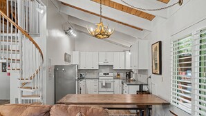 Eine moderne Küche mit weißen Schränken, einem Holztisch und einem eingebauten Backofen.