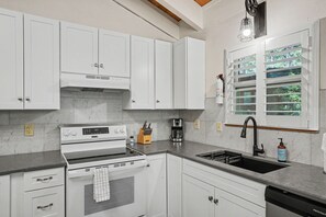 A modern kitchen with white cabinets, a built-in oven, a coffee maker, and a window with blinds. - Steps to Heavenly | Mountain Chalet w/ Hot Tub (South Lake Tahoe)