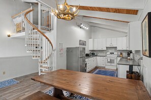 A modern kitchen with white cabinets, a wooden dining table, and a spiral staircase. - Steps to Heavenly | Mountain Chalet w/ Hot Tub (South Lake Tahoe)