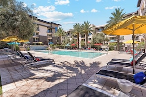 A poolside area with sun loungers, umbrellas, and a clear blue pool. - Luxury Midtown Stay • Pool • Hot Tub • Near Downtown • King Bed (Phoenix)