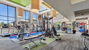 Ein Fitnessstudio mit unterschiedlichen Trainingsgeräten, großen Fenstern und Blick ins Freie.