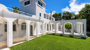 A modern building with a white exterior, multiple arches, and a well-maintained lawn.