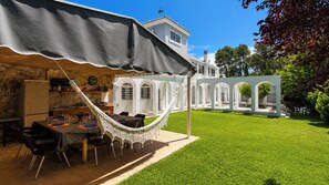 A patio with a dining table, chairs, and a hammock.