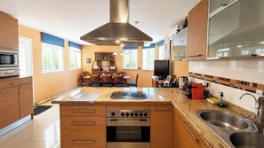 A modern kitchen with a central island, built-in oven, and stainless steel appliances.