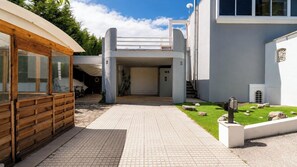 A modern building with a covered entrance, a paved pathway, and a small garden area.