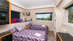 A bedroom with two beds, a window with a view, and a radiator.