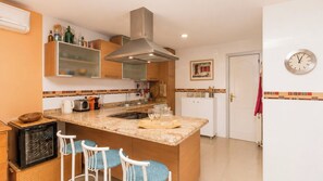 A kitchen with a central island, bar stools, a microwave, and a built-in oven. - La Luna Albolote by Ruralidays (Granada)