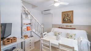 Ein Zimmer mit einem Bett, einem Fernseher, einem Esstisch und einer Treppe.