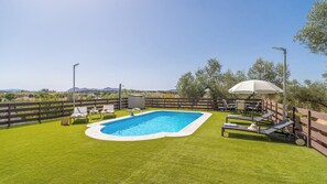 En trädgård med en pool, omgiven av ett trästaket, och inredd med utemöbler.