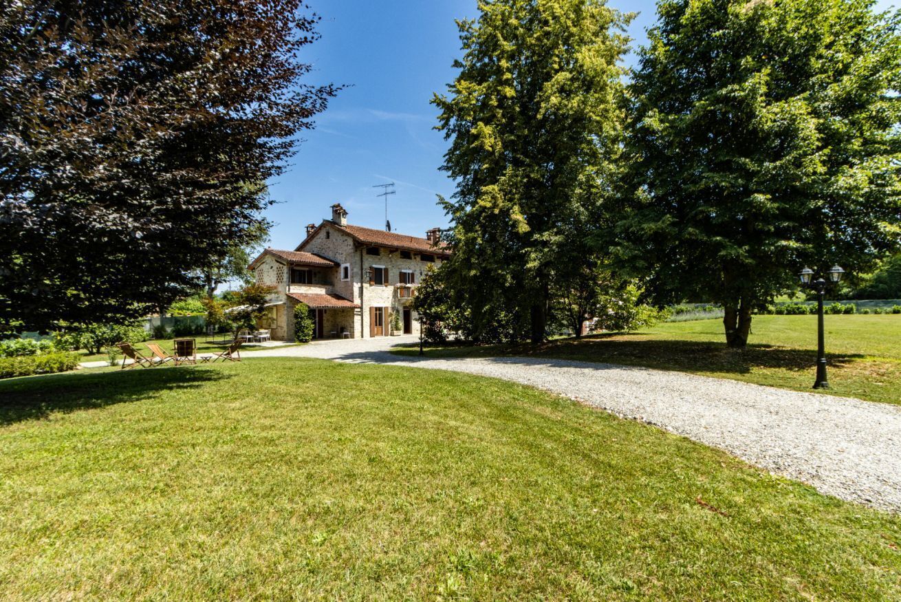 Ein Haus mit Kopfsteinpflasterauffahrt, umgeben von Bäumen und einem gepflegten Rasen.
