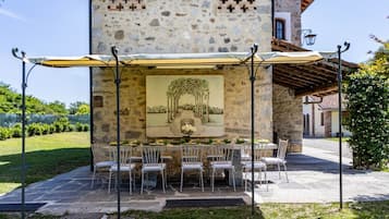 An outdoor dining area with stone walls, a mural, and a covered table with chairs.