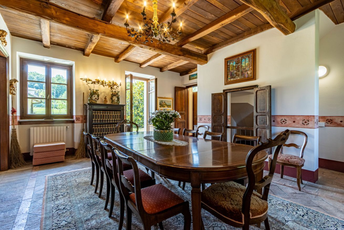 A dining room with a wooden table, chairs, and a chandelier.