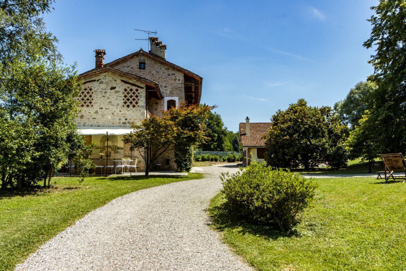 A stone building with a gravel path leading to it, surrounded by greenery.