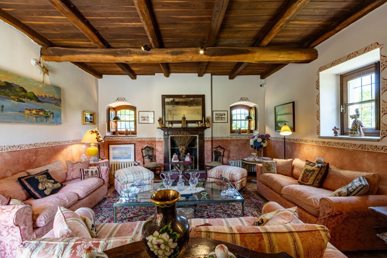 A traditional living room with a fireplace, two sofas, a coffee table, and a large mirror.