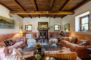 A traditional living room with a fireplace, two sofas, a coffee table, and a large mirror. - Villa Harmonia - Luxury Rooms - Rosa Suite - AC - By Guestaly (Dormelletto)