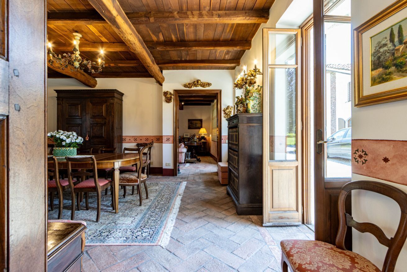 A traditional interior with a wooden ceiling, a dining area with chairs and a table, and a large cabinet.