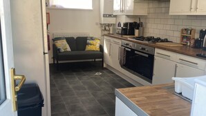 Et lille køkken med en sofa, en skraldespand og et køleskab.
