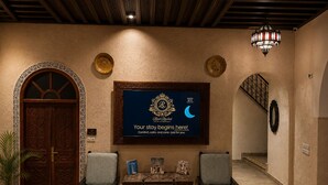 A hotel lobby with a reception desk, two armchairs, a chandelier, and a framed welcome sign. - Riad Rachid – Private Riad with Pool (13 Guests) (Meknès)