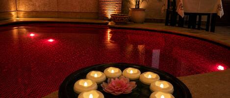 Un área de piscina con una disposición circular de velas y un centro de flores de loto.