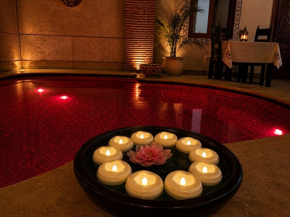 A pool area with a circular arrangement of candles and a lotus flower centerpiece.