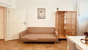 Ein Wohnzimmer mit einer Couch, einem Holzschrank und einem gerahmten Bild an der Wand.