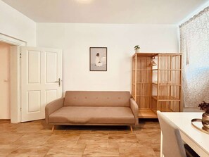 Ein Wohnzimmer mit einer Couch, einem Holzschrank und einem gerahmten Bild an der Wand.