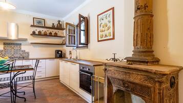 Een keuken met een kookplaat, oven, spoelbak en decoratieve planken.