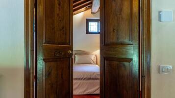 Een houten deur die leidt naar een slaapkamer met een bed en een raam.